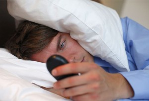 photolibrary_rf_photo_of_man_checking_cellphone_in_bed